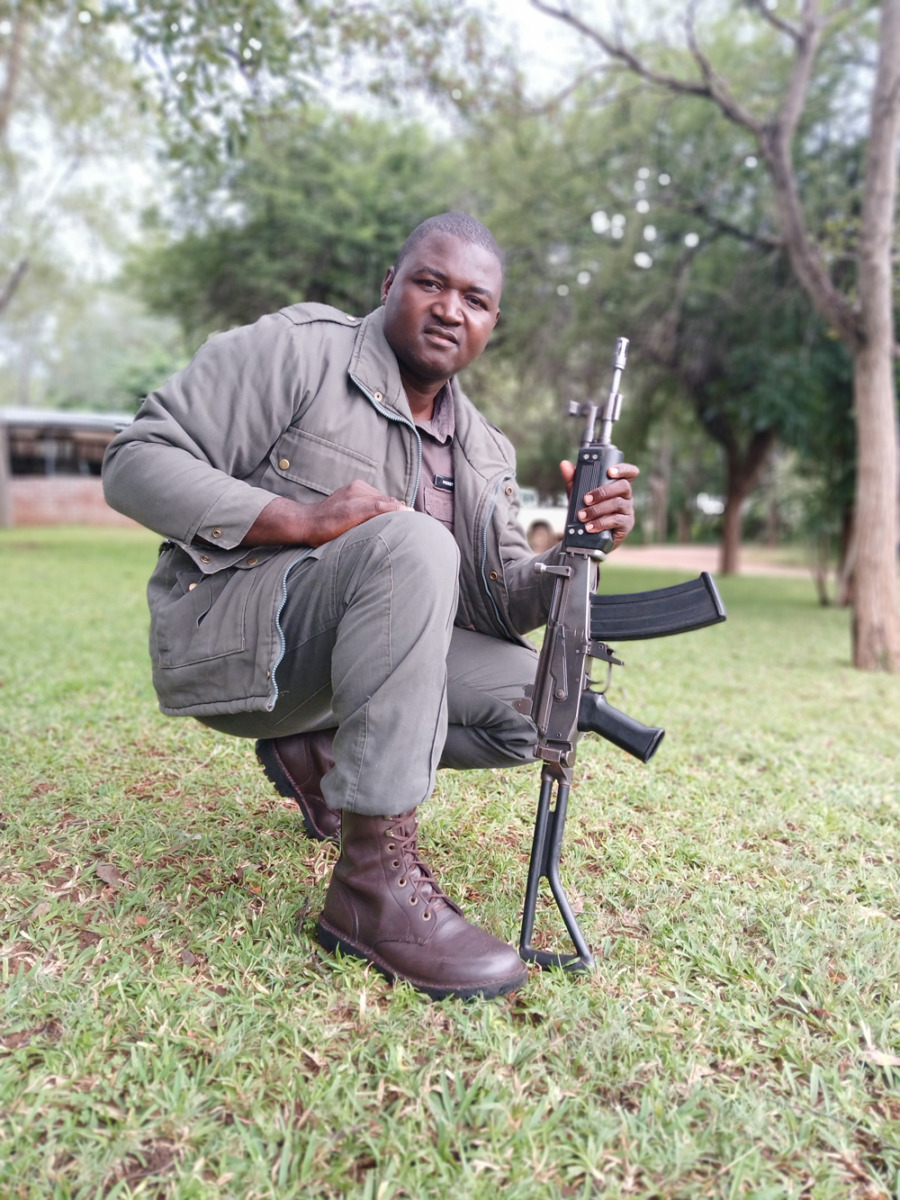 Picket kneeling in the grass holding a rifle
